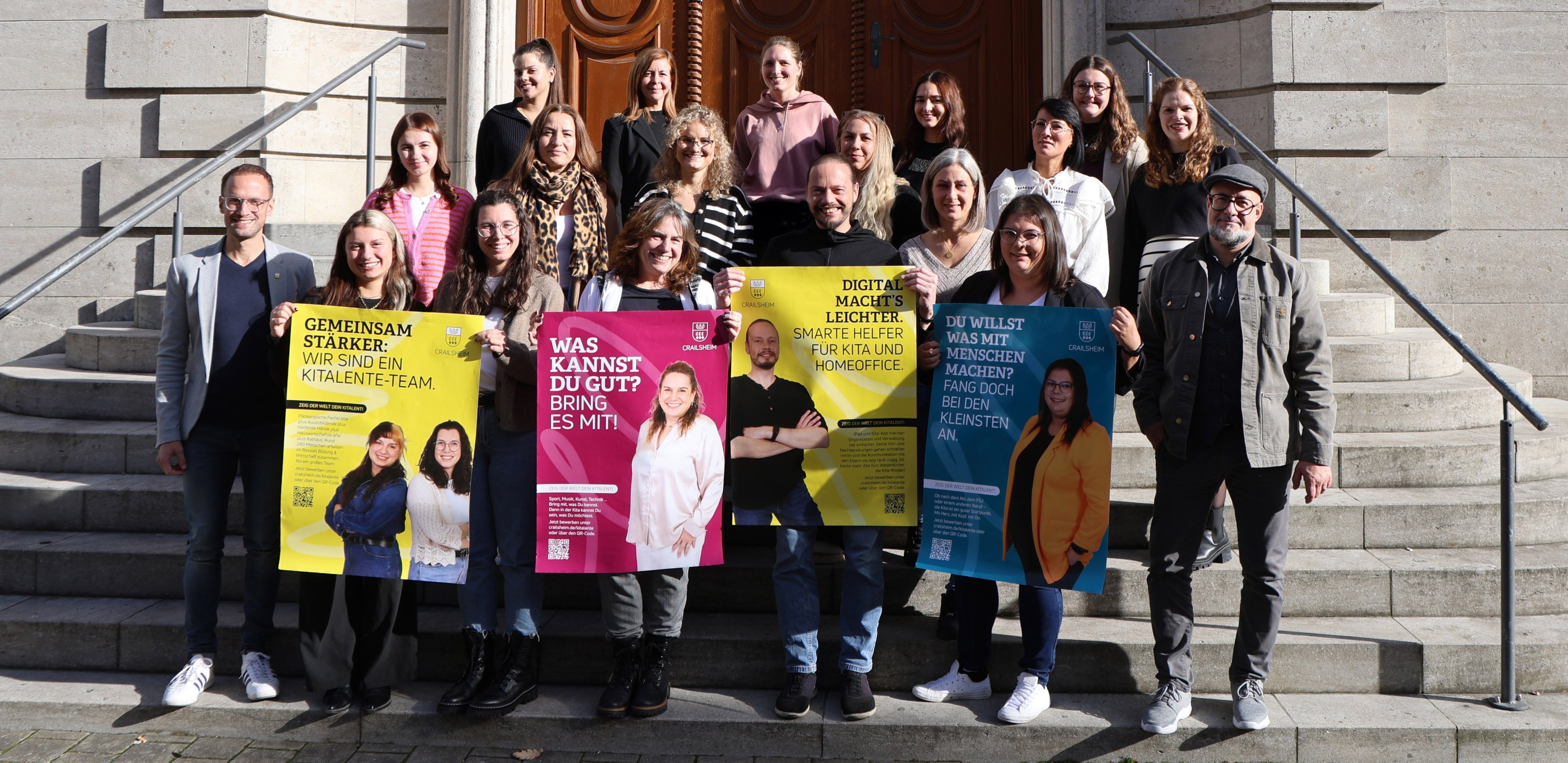 Gruppenfoto, auf dem Erzieherinnen und Erzieher zu sehen sind, die Plakate mit den Kampagnenmotiven in die Kamera halten.