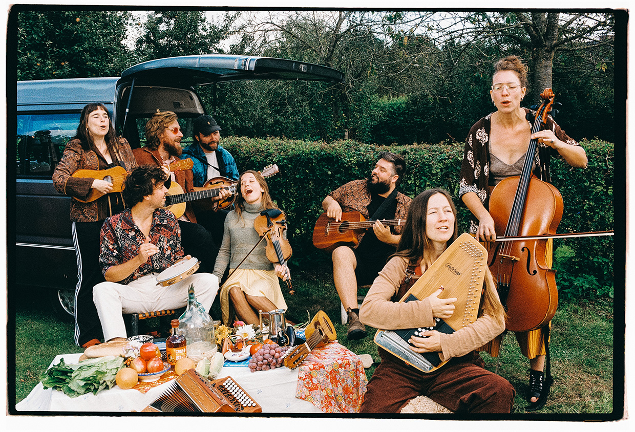 eine Musikergruppe sitzt um eine Picknickdeckeherum