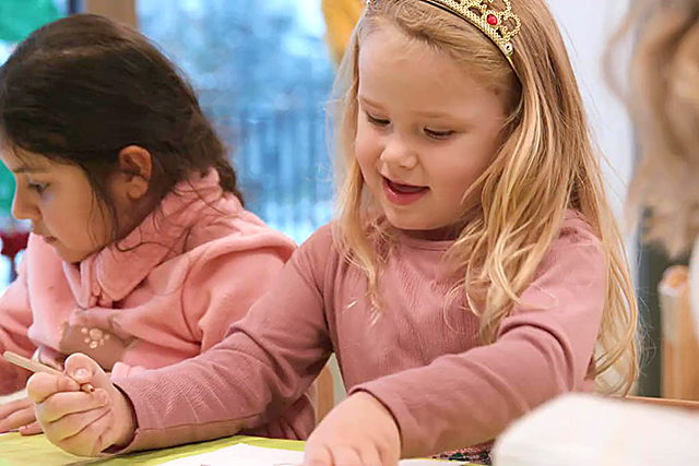 Zwei Mädchen sitzen nebeneinander und malen.